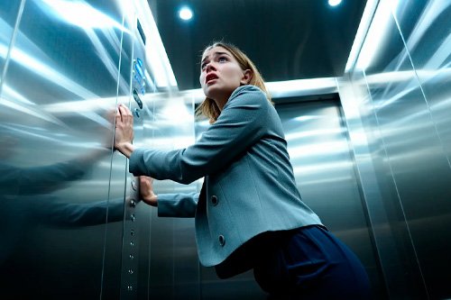 Девушка в стрессе из-за замкнутого помещения Девушка стоит в лифте